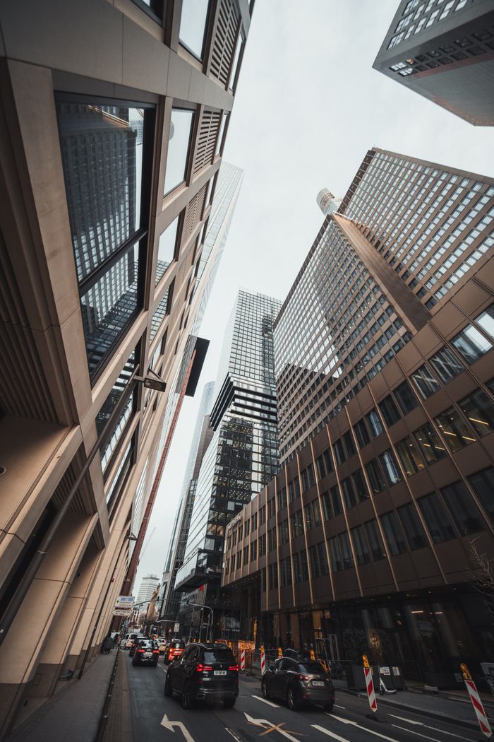 Tall modern buildings in a bustling city street with traffic.